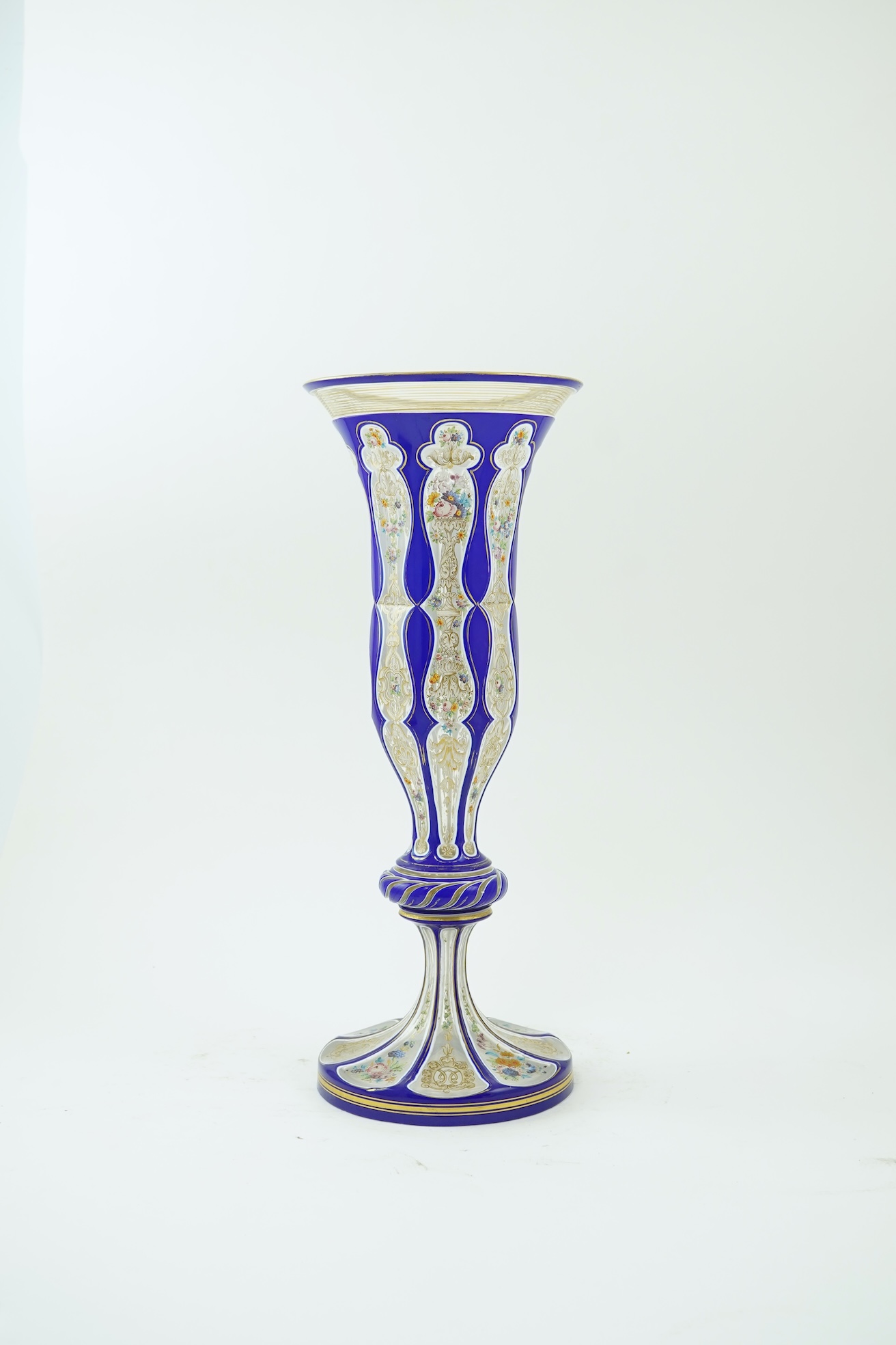A tall 19th century Bohemian blue and white overlaid gilt and enamel decorated vase in the manner of Moser